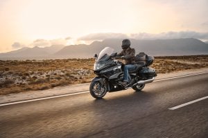 BMW K 1600 Grand America rider on an open road at sunset